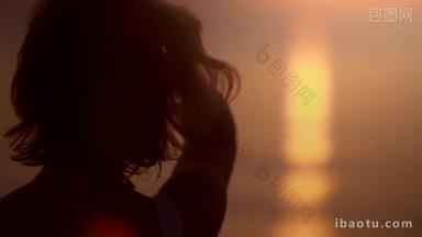 轻松自在的女游客在日落时欣赏着迷人的海景，<strong>回放</strong>着她的头发